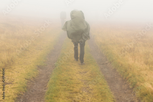 Woman with backpack hiking in the fog.