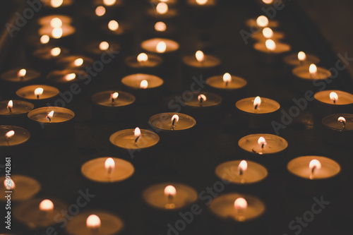 soft focus atmospheric photography of candles in catholic church interior with blurred bokeh glares background 