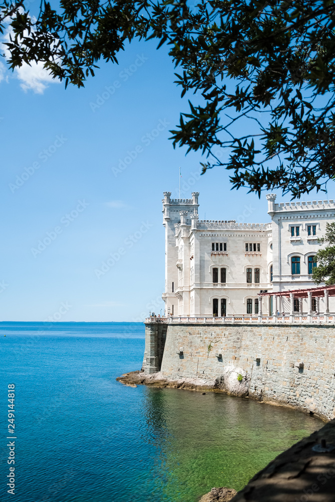 Miramare castle facing the gulf waters shot from aside and under an olive twig