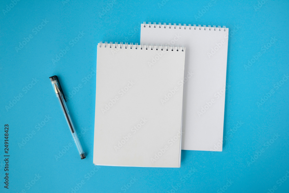 school notebook on a blue background, a spiral notebook on the table and a pen school notebook on a blue background, a spiral notebook on the table and a pen