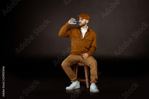 Handsome young man in beige clothes drinking water