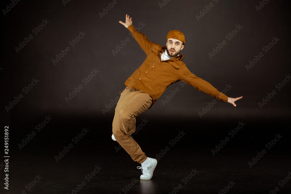 Young and handsome man in beige clothes standing in dance pose