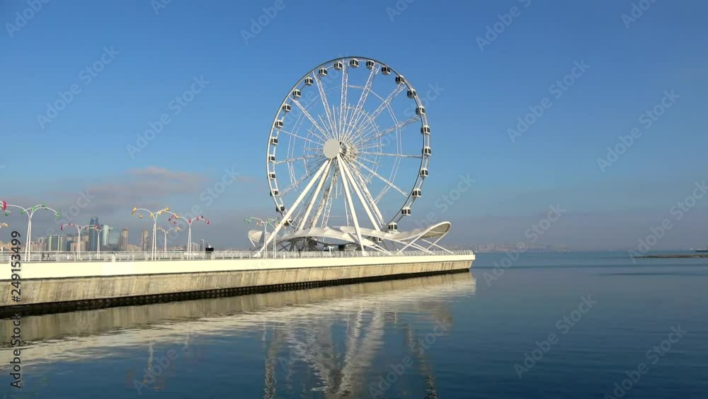 View of the Ferris wheel on the Caspian sea. Sunny January day (timelapse). Baku, Azerbaijan View of the Ferris wheel on the Caspian sea. Sunny January day (timelapse). Baku, Azerbaijan