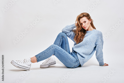 Fotografia What do you mean? Brown-haired, cute girl sitting on the floor, touching her hai