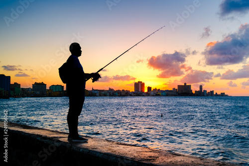 Silhouette of a man fishing on the bay of Havana at sunset