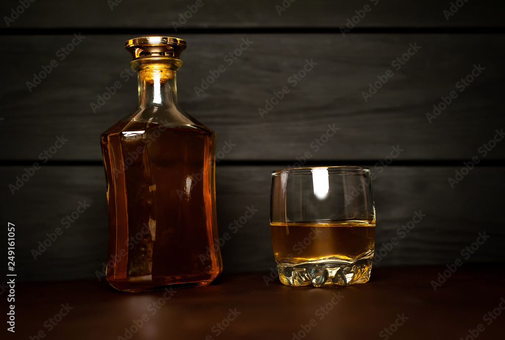 bottle of whiskey and a glass of whiskey on a wooden background bottle of whiskey and a glass of whiskey on a wooden background
