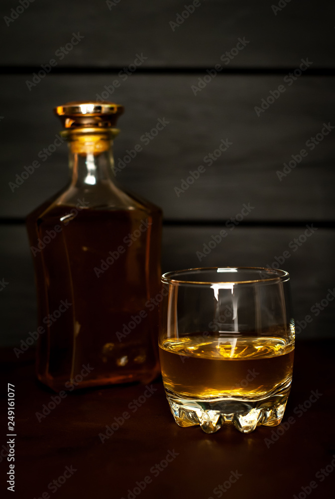 bottle of whiskey and a glass of whiskey on a wooden background bottle of whiskey and a glass of whiskey on a wooden background