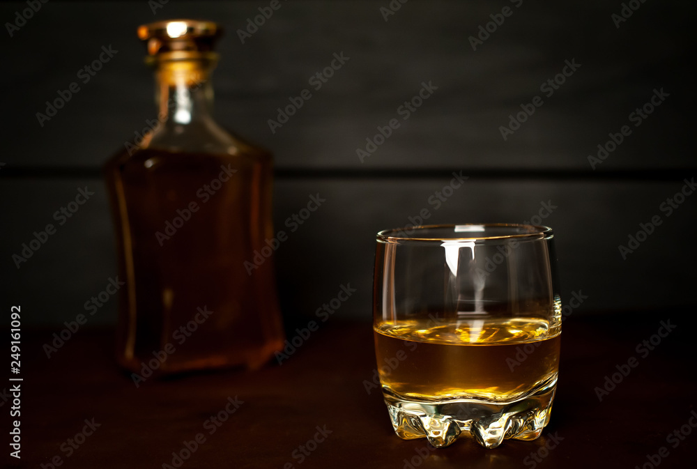 bottle of whiskey and a glass of whiskey on a wooden background bottle of whiskey and a glass of whiskey on a wooden background