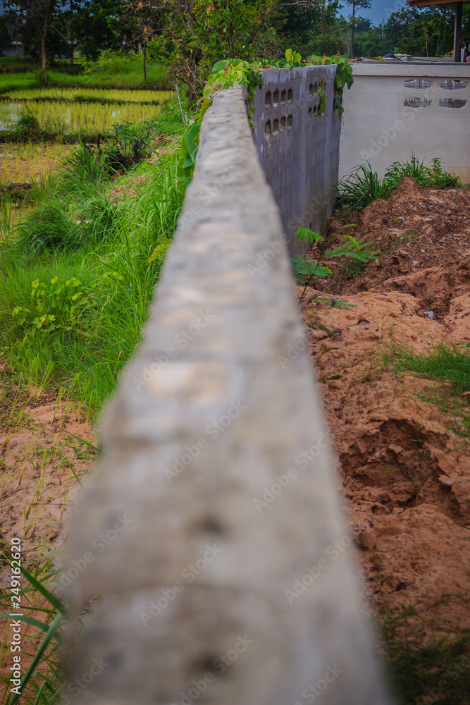 Fence wall of the newly built housing is tilted and collapsed due to high earthwork and heavy rainfall, causing the soil in the house to weaken and flow out with the water although there are drains.