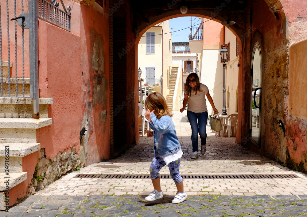 Little girl plays with her mother in a small and characteristic Italian village. San Felice Circeo, Lazio, Italy