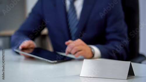 Man in business suit working on tablet pc, blank nameplate template for text
