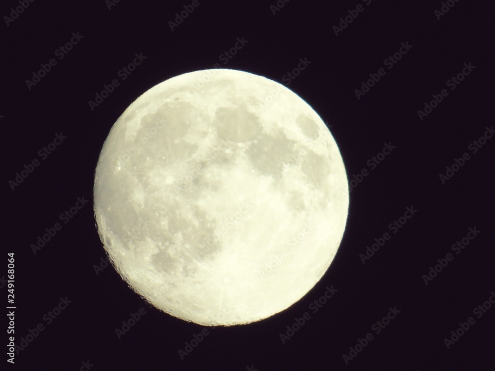 Fototapeta premium Genova, Italy - 10/24/2018: An amazing photography of the full moon over the city of Genova by night with a great clear sky in background and some stars using high zoom.