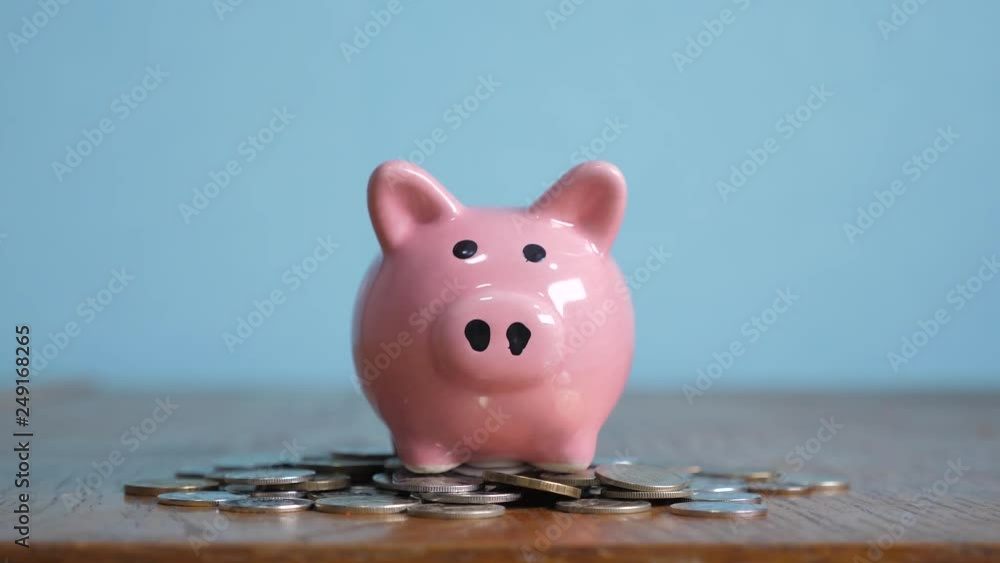piggy bank business standing on a pile of coins concept. A hand is putting coin in a piggy bank on a yellow background. saving money is an investment for the future. Banking investment and finance
