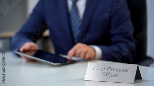 Male chief financial officer planning company budget on tablet pc, office work