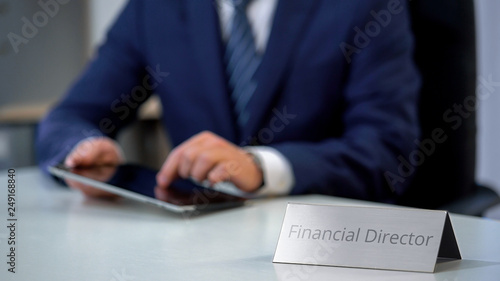 Financial director in suit scrolling on tablet pc, watching corporative files