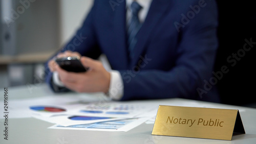 Φωτογραφία Notary public holding smartphone and working with documents, analyzing data
