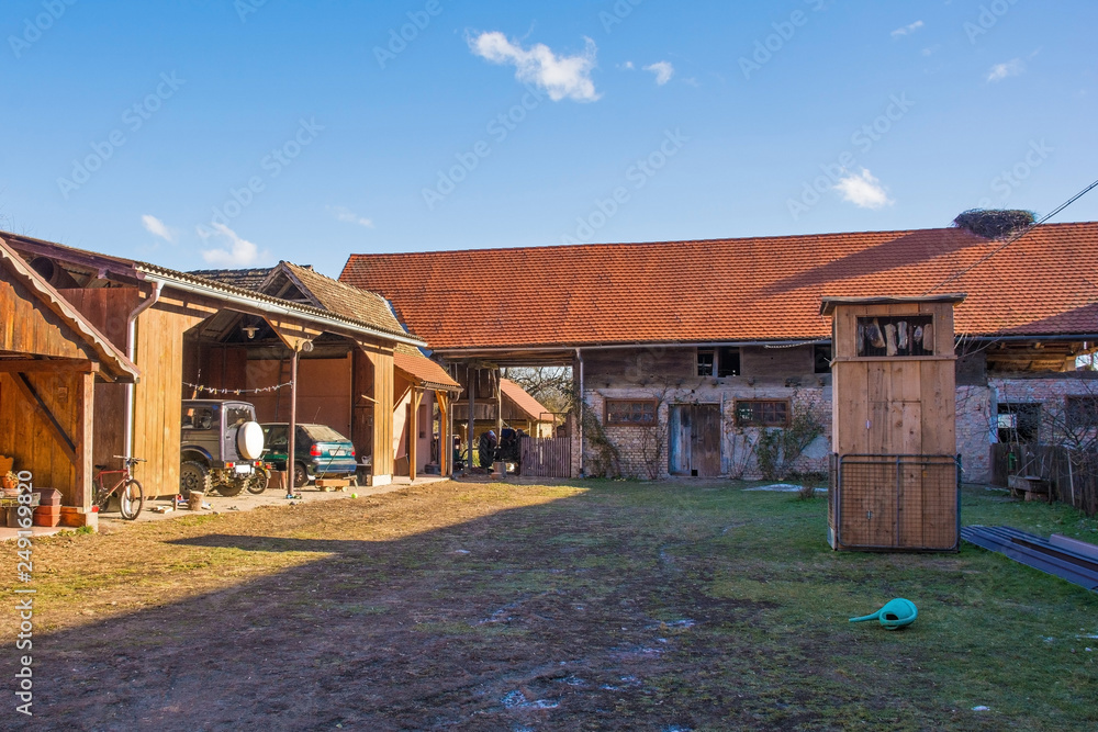 A small farm yard in the village of Cigoc in Sisak-Moslavina County in central Croatia. The central wooden tower is for curing dried meats away. A stork nest can be seen on the roof on the far right