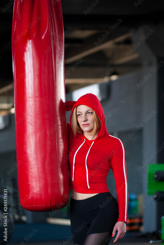 Attractive woman posing with punching bag. Lady boxer. Girl after kickboxing training 