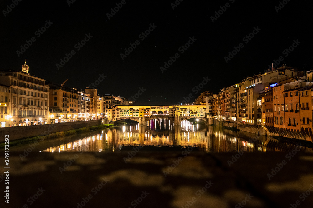 Le luci del Ponte Vecchio di Firenze di notte riflesse sul fiume Arno