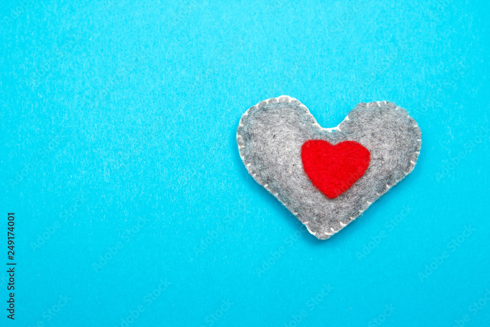 Obraz premium Felt handmade heart on a blue background. Top view.