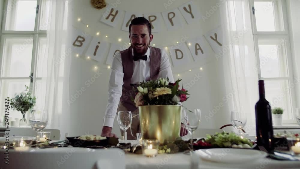 A portrait of a young man standing indoors in a room set for a party. Slow motion. A portrait of a young man standing indoors in a room set for a party. Slow motion.