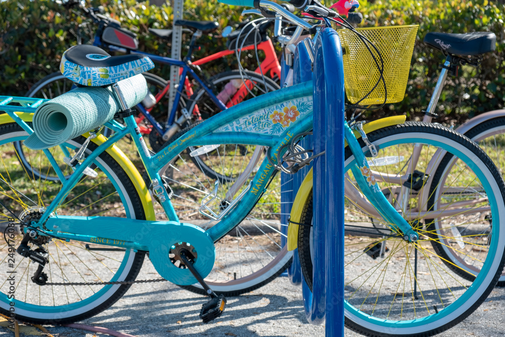 Colorful bikes parked on bike rack with yoga mat tied to the back