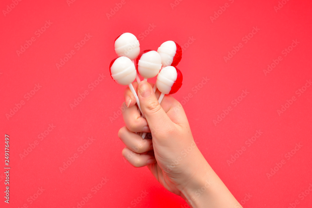 Lollipop in female hand on red background. Space for text or design. Lollipop in female hand on red background. Space for text or design.