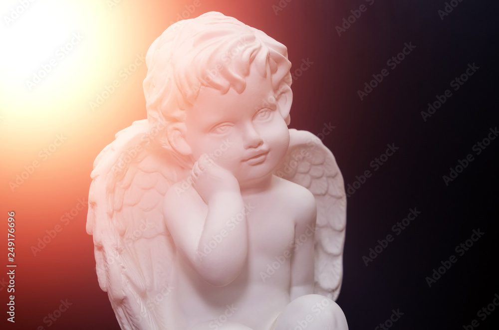 Beautiful white angel on black background close-up with flare