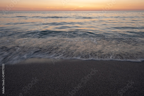 Long exposure of waves on beach at sunrise © Liam