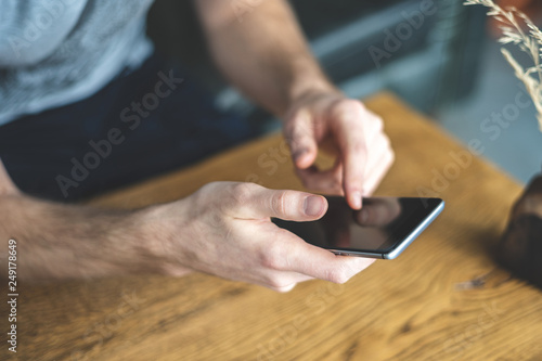 Man holding cellular in hands over wooden table