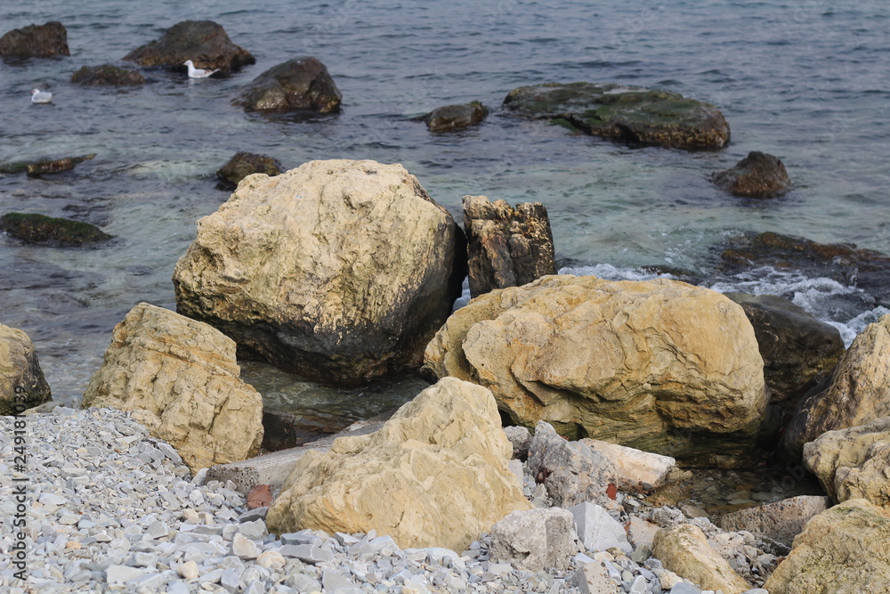 Large stones lie near the shore in seawater.