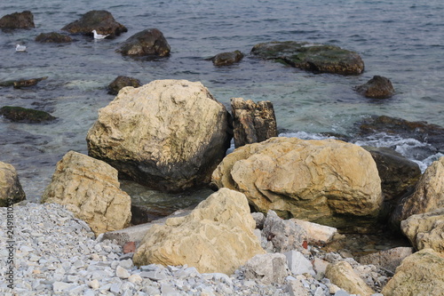Large stones lie near the shore in seawater. © ozrolf