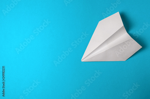 Flat lay of white paper airplane on blue color background. Copy space 