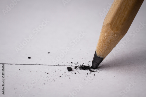 Close up of broken pencil with drawing line on textured white paper