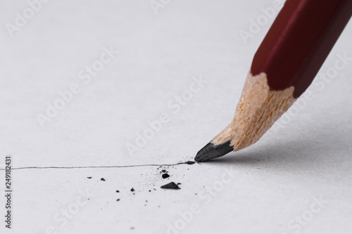 Close up of broken pencil with drawing line on textured white paper