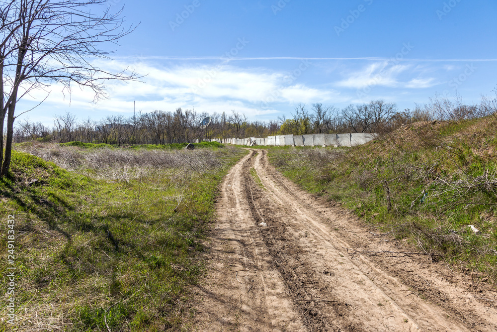 Unpaved country road without asphalt. A rough nameless dirt road on the outskirts of Ukraine. Stony roads in the steppe. Dirty road without pavement runs into perspective into the distance Unpaved country road without asphalt. A rough nameless dirt road on the outskirts of Ukraine. Stony roads in the steppe. Dirty road without pavement runs into perspective into the distance