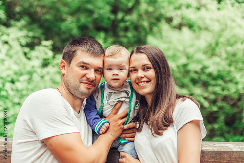 Happy loving young family with infant baby walking together in green summer park hugging each other. Family, togetherness, childhood concept © Andreshkova Nastya