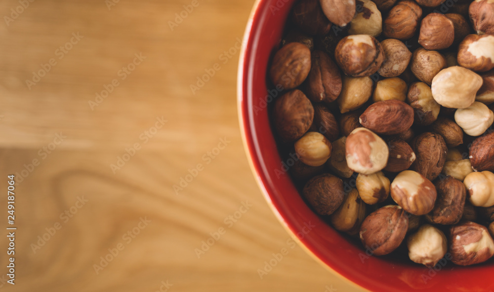 Fototapeta Hazelnuts in bowl on wooden background