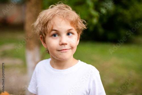 Blonde smiling boy with strabismus in warm park photo