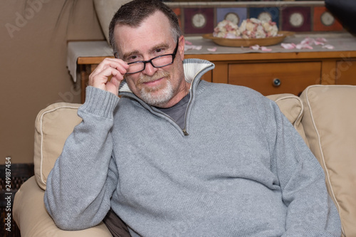 senior man reading an old book adjusts glasses