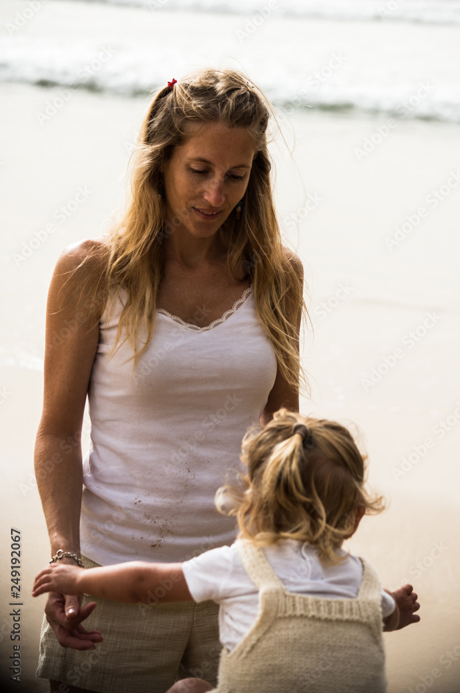 mother and daughter playing together in an empty beach during summer