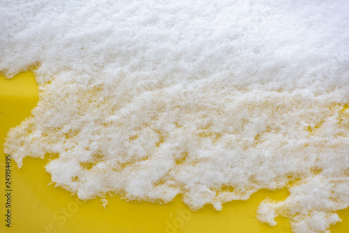 Bright yellow car surface covered with white snow photo