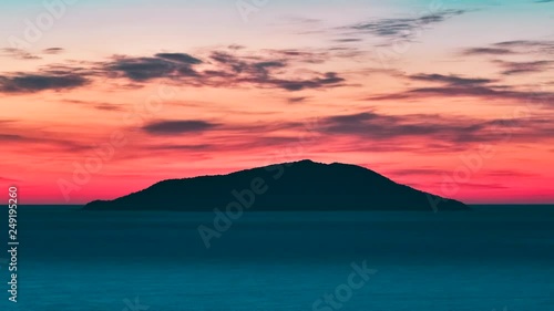 Timelapse video of a small island silhouette in the middle of the sea at sunrise, Colorful sky with red, cyan and blue tones. Day rising. Ilha do Arvoredo - Bombinhas SC, Brazil. photo