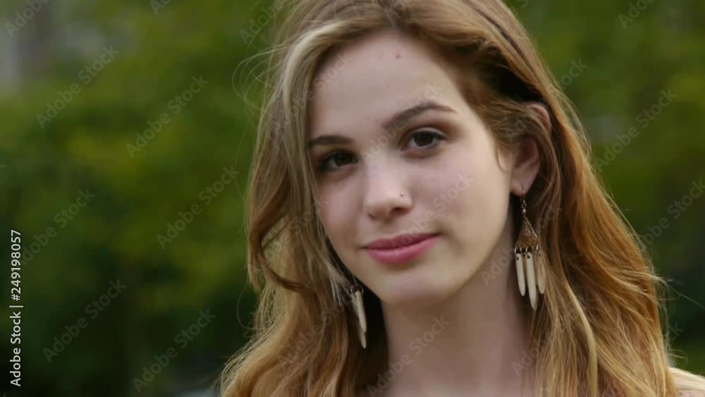 Young Woman, Standing In A City Park, Smiles At Camera Young Woman, Standing In A City Park, Smiles At Camera