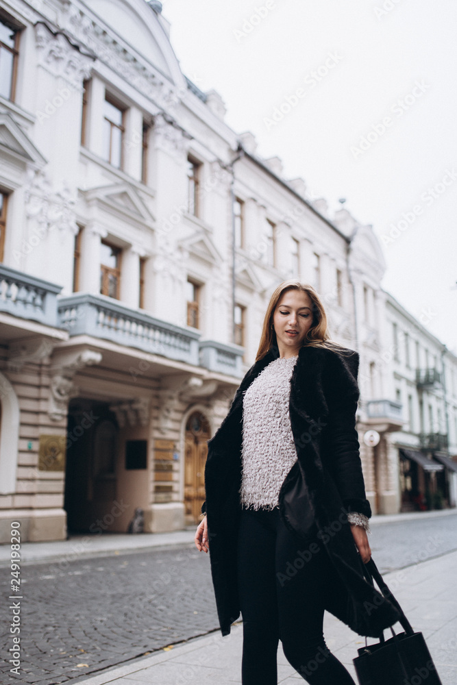 Fototapeta premium Young blondie business woman rushing to a business meeting. Walking along old historic european town