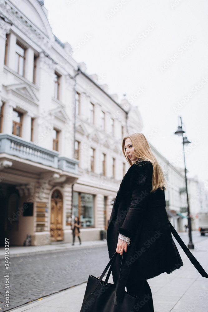 Fototapeta premium Young blondie business woman rushing to a business meeting. Walking along old historic european town 