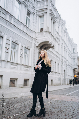 Young blondie business woman rushing to a business meeting. Walking along old historic european town 
