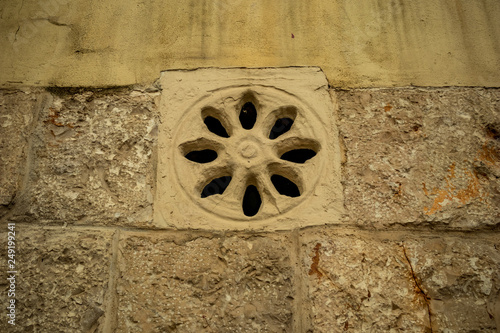 External eight leaves rose-window, yellow limestone fenestra, on residential building in the historic center of Altamura, Italy, Puglia region