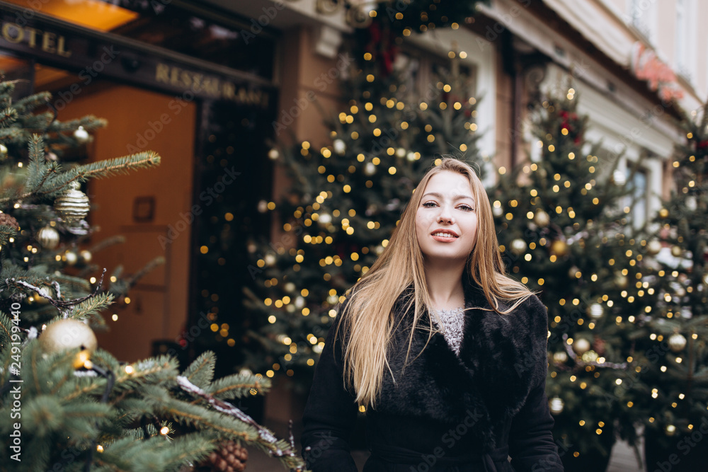 Young blondie cheerful girl in chrismas decorated city street. Beauty, holiday, youth, emotional concept Young blondie cheerful girl in chrismas decorated city street. Beauty, holiday, youth, emotional concept