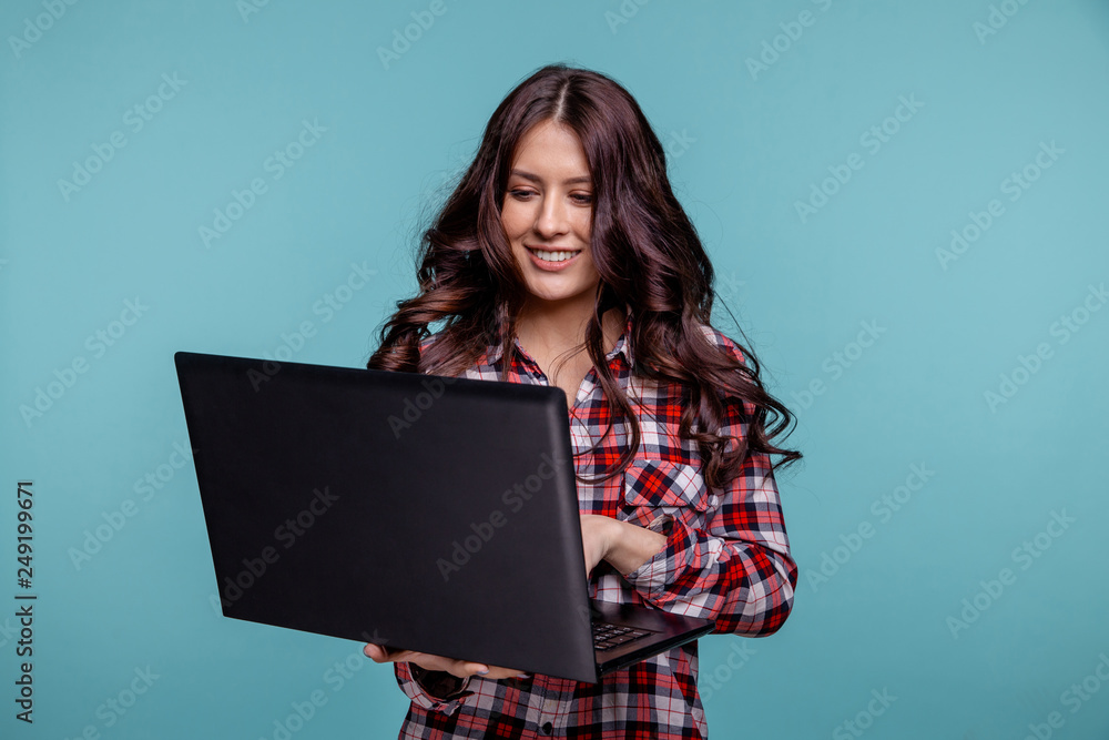 Portrait of an excited young girl holding laptop computer and celebrating success isolated over blue background Portrait of an excited young girl holding laptop computer and celebrating success isolated over blue background